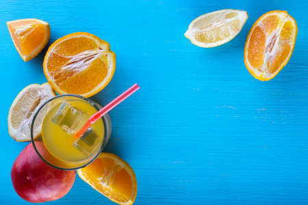 Fresh raw fruits and glass of juice on blue backgroundの写真素材