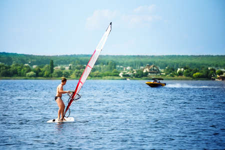 Windsurfer on board with a white sail floating awayの写真素材