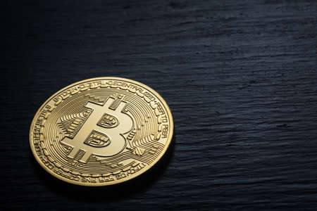 Golden shiny bitcoin on a black wooden backgroundの写真素材