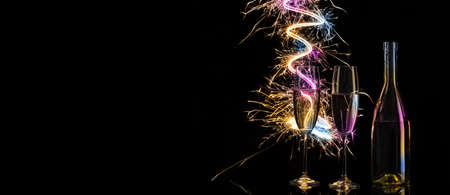 Glasses and bottle of champagne in shining of colored Bengal ligの写真素材