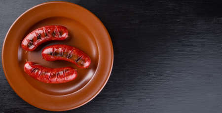 Round clay dish with toasted apetit sausagesの写真素材