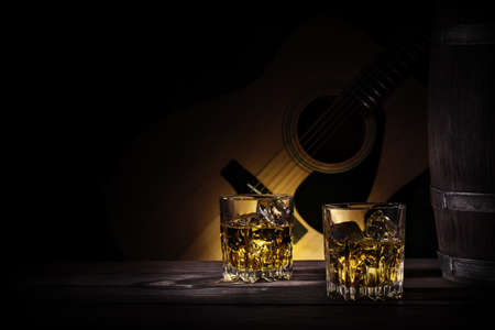 Glasses and barrel of whiskey on background of guitarの写真素材