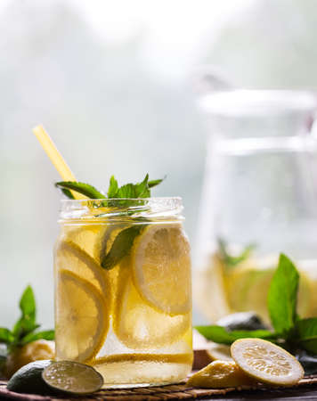 Cold fresh lemonade in transparent jar with lemon wedges and minの写真素材