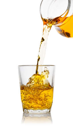 Apple juice pours from the decanter into transparent glassの写真素材