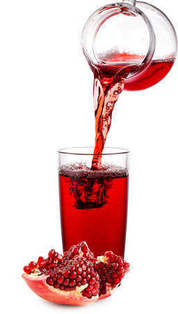 Pomegranate juice poured from jug into glassの写真素材