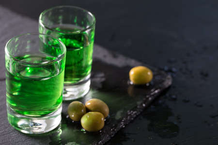 Two glasses of strong absinthe and green olivesの写真素材