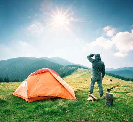 Man on mountain near orange tent looks into the distanceの写真素材