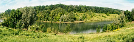 Bend of the river with green trees and grass on the shore. Summer landscape. The concept of travel freedom and privacyの写真素材