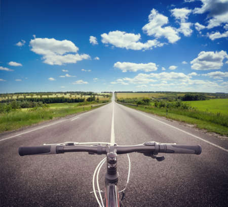 Bicycle steering wheel on an asphalt road under a cloudy skyの写真素材
