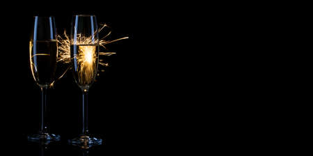 Two glasses of champagne in bright sparks on a black backgroundの写真素材