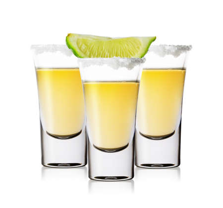 Three glasses of golden tequila with salt and limeの写真素材