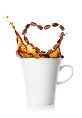 Splash in cup of coffee from grains falling in shape of heartの写真素材