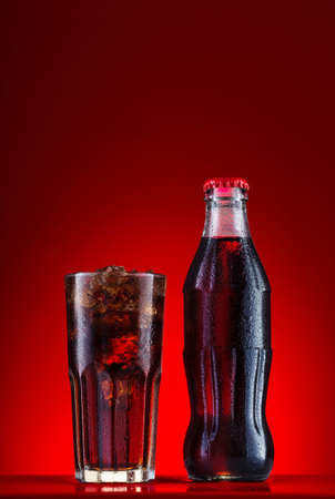 Brown carbonated drink in bottle and glass with iceの写真素材
