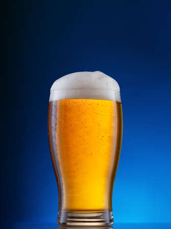 Glass with light beer on blue backgroundの写真素材