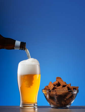 Salty rye crackers and beer pouring into glassの写真素材