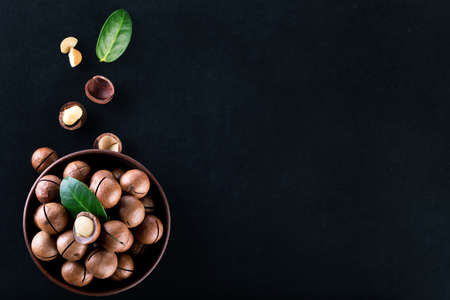 Macadamia nuts in plate with grains and leaves on black backgroundの写真素材