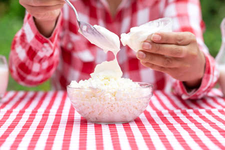 Woman puts sour cream in cottage cheeseの写真素材