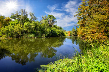 Blue river or lake with green trees on the shoreの写真素材