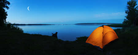 Orange tourist tent on shore of lake at duskの写真素材
