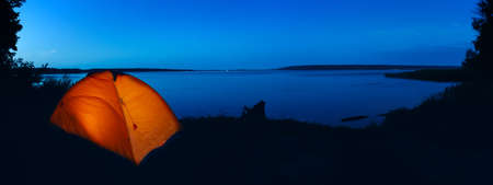Orange lighted tent on lakeの写真素材