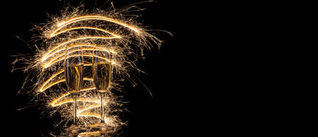 Two glasses of champagne in bright festive lights on black background. Concept for celebrating Christmas, New Year and other celebrationsの写真素材