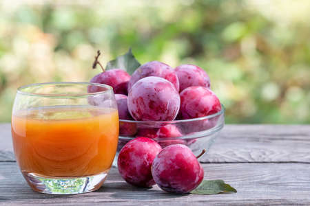 Plum juice and plums on wooden tableの写真素材