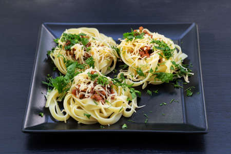 Spaghetti with meat grated cheese and herbs on black square plateの写真素材