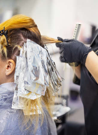 Hands of hairdresser in black gloves dye your hairの写真素材