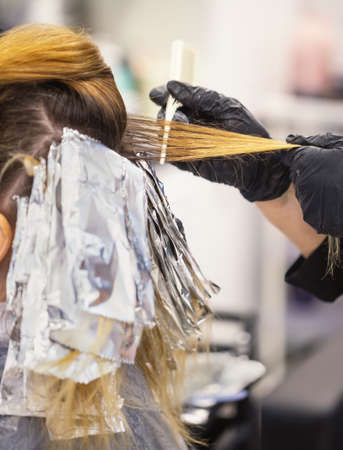 Master in black gloves dyes hair to woman at hairdresserの写真素材