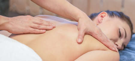 Hands of massage therapist doing massage on back of young girlの写真素材