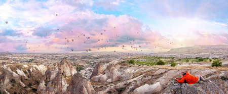 Man takes pictures of balloons on his phone in sky over Cappadociaの写真素材