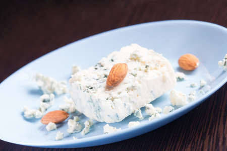 Blue cheese and almonds on plate on wooden backgroundの写真素材