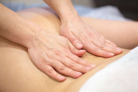 Hands of woman masseur on back of patientの写真素材