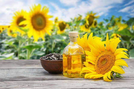 Sunflower oil with flowers and sunflower seeds on a wooden tableの写真素材