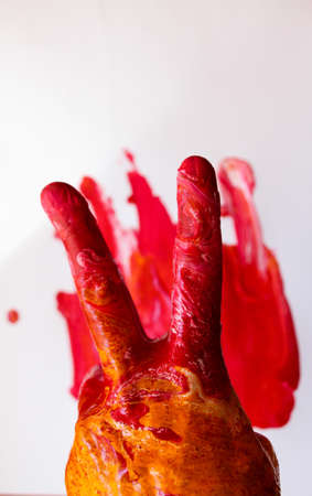 Hand - two fingers in multi-colored paint on a white background with spots.の写真素材