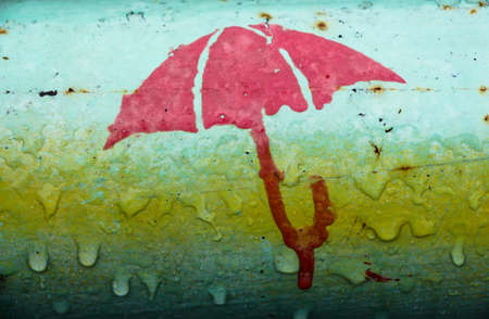 Figure of an umbrella on an iron pipe. The photo was taken during the rain and it shows that the...