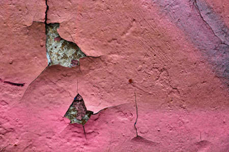 The texture of the pink paint on the old wall, which from time to time became cracked, turned out to be a chic background and a colorful abstraction.の写真素材