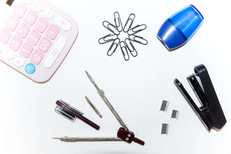 Accessories for the learning process-calculators, clips, compasses and accessories for the compass, stapler, staples, pencil sharpener. Subjects for the schoolboy. The first of September.の写真素材