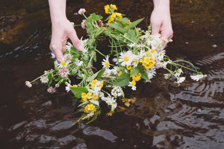 The girl is holding a wreath of flowers in her hands.の写真素材