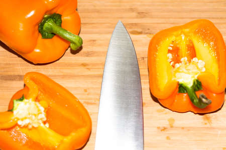 Orange peppers are cut with a knife on a cutting board