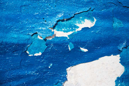 Texture of a blue cracked blue paint on a concrete wallの写真素材