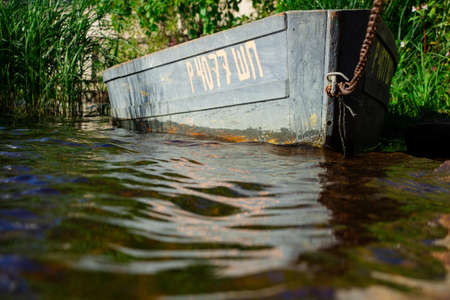 The boat of fishermen is tied with a thick chain on the shore of a clean lakeの写真素材