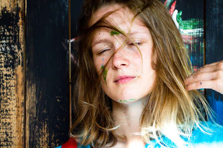 A beautiful and young girl with a disorderly hairstyle With her hair, she stands beside the painted.の写真素材