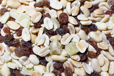 On a white background. The mixture consists of peanuts, candied fruits, raisins and dried bananas.