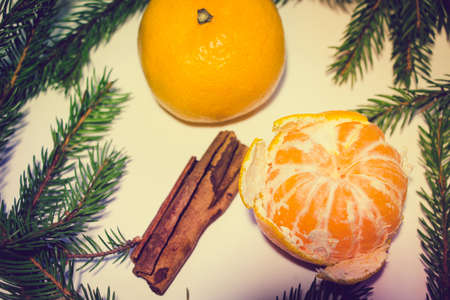 Two mandarins, one of which is peeled, lie on a white background. Around the tangerines are branches...