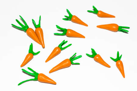 Several carrots on a white background made of plasticine. Carrots lie randomly with each other.