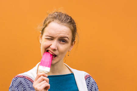 Beautiful girl with pink ice cream and enjoys. But still to enjoy. She stands against a pink shade.の写真素材