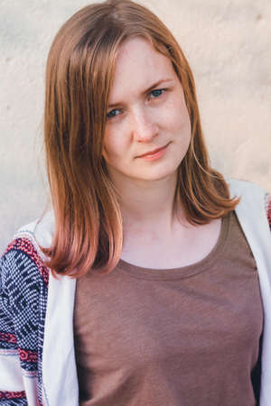 A beautiful and young girl stands on a neutral background. The girl is dressed in beautiful clothes....
