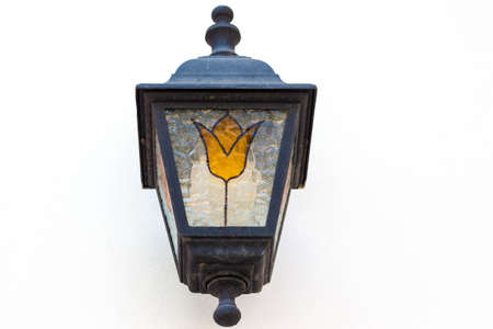 Vintage lantern on the wall in white. A yellow flower is painted on a metal lamp.の写真素材
