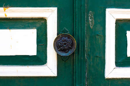 Doorknob on an old green door. The handle is engraved with a pattern in the form of rose flowers.の写真素材